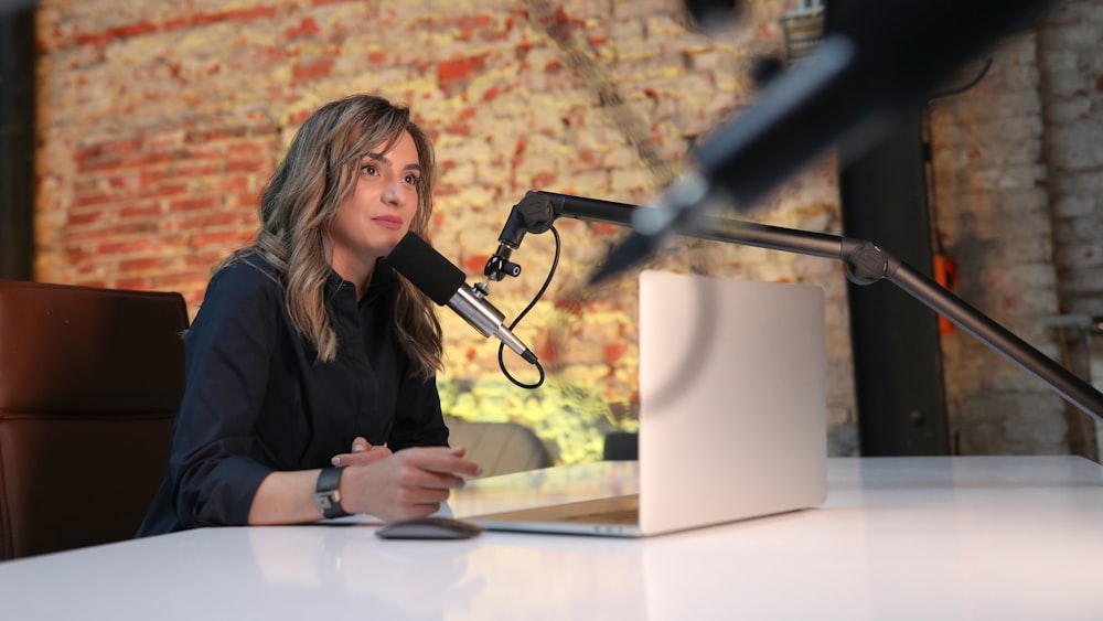 a woman sitting at a table in front of a microphone