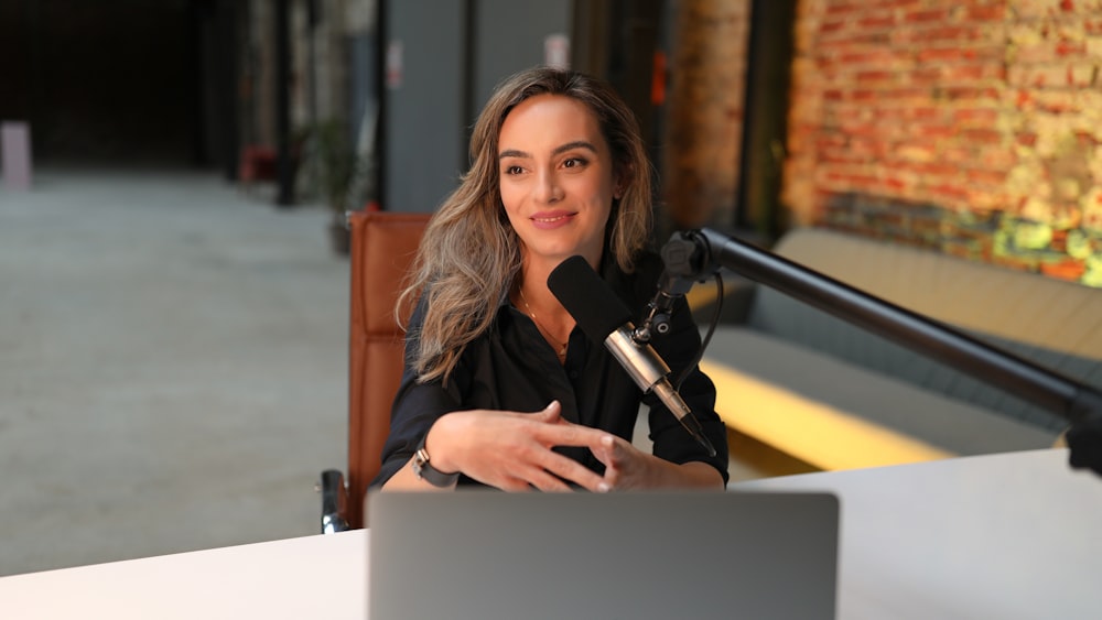 a woman sitting at a table with a microphone in front of her