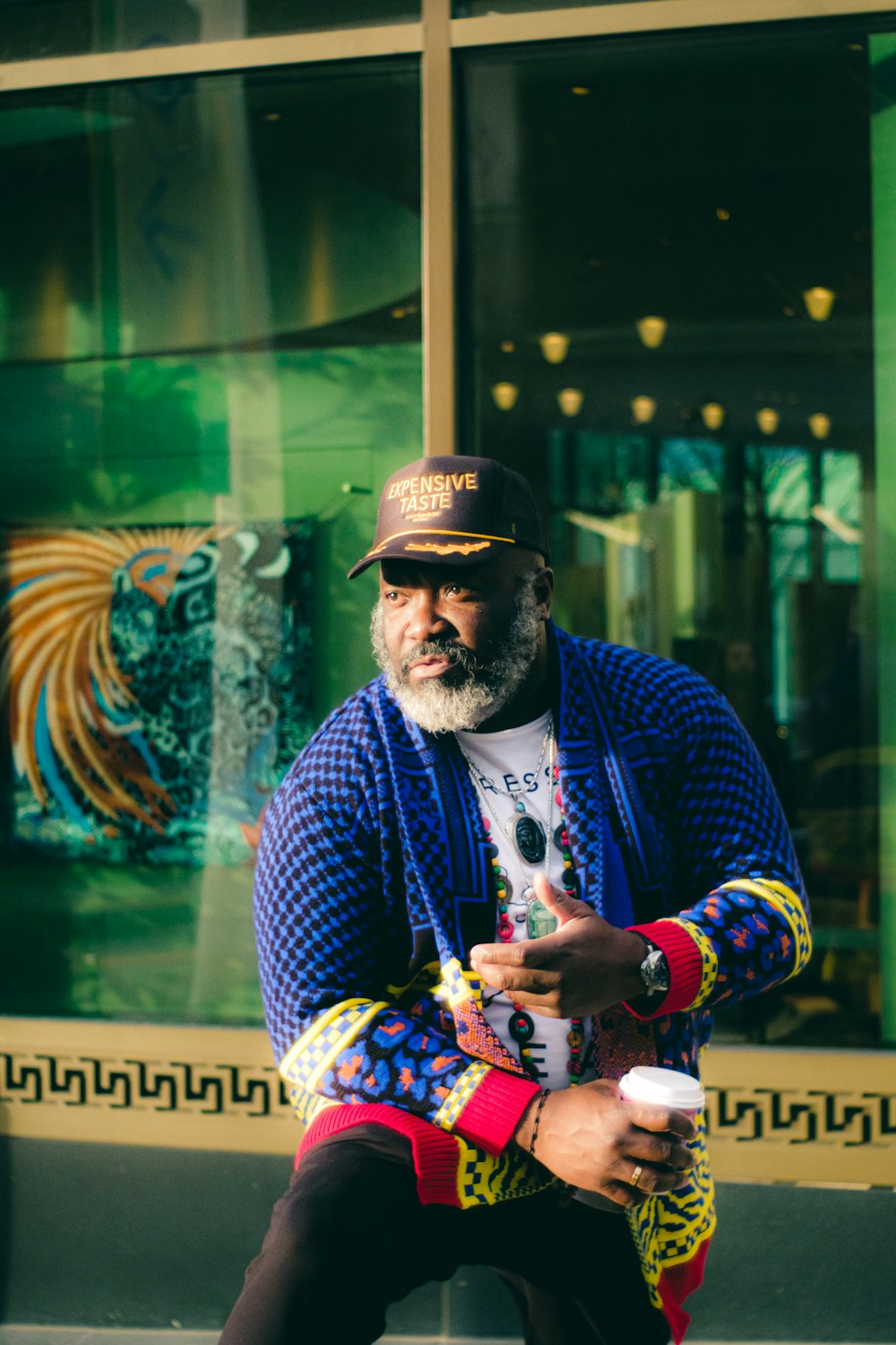 a man sitting on a curb with a cup of coffee