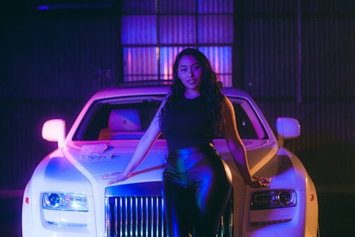 An influencer posing confidently next to a high-end electric vehicle.