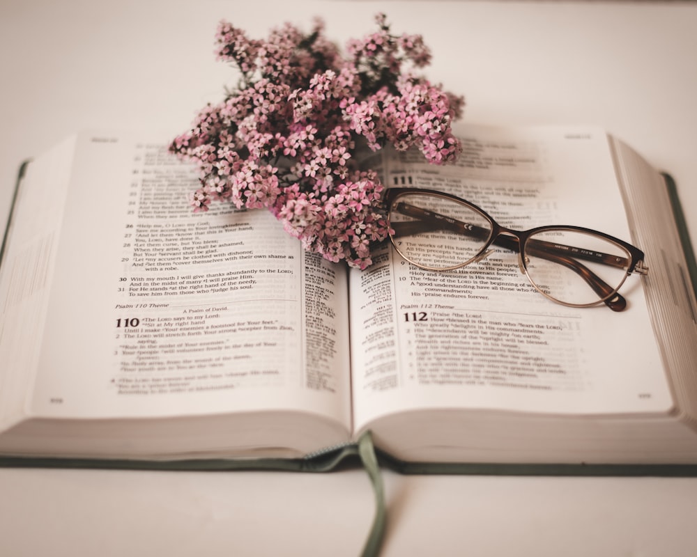 an open book with glasses on top of it