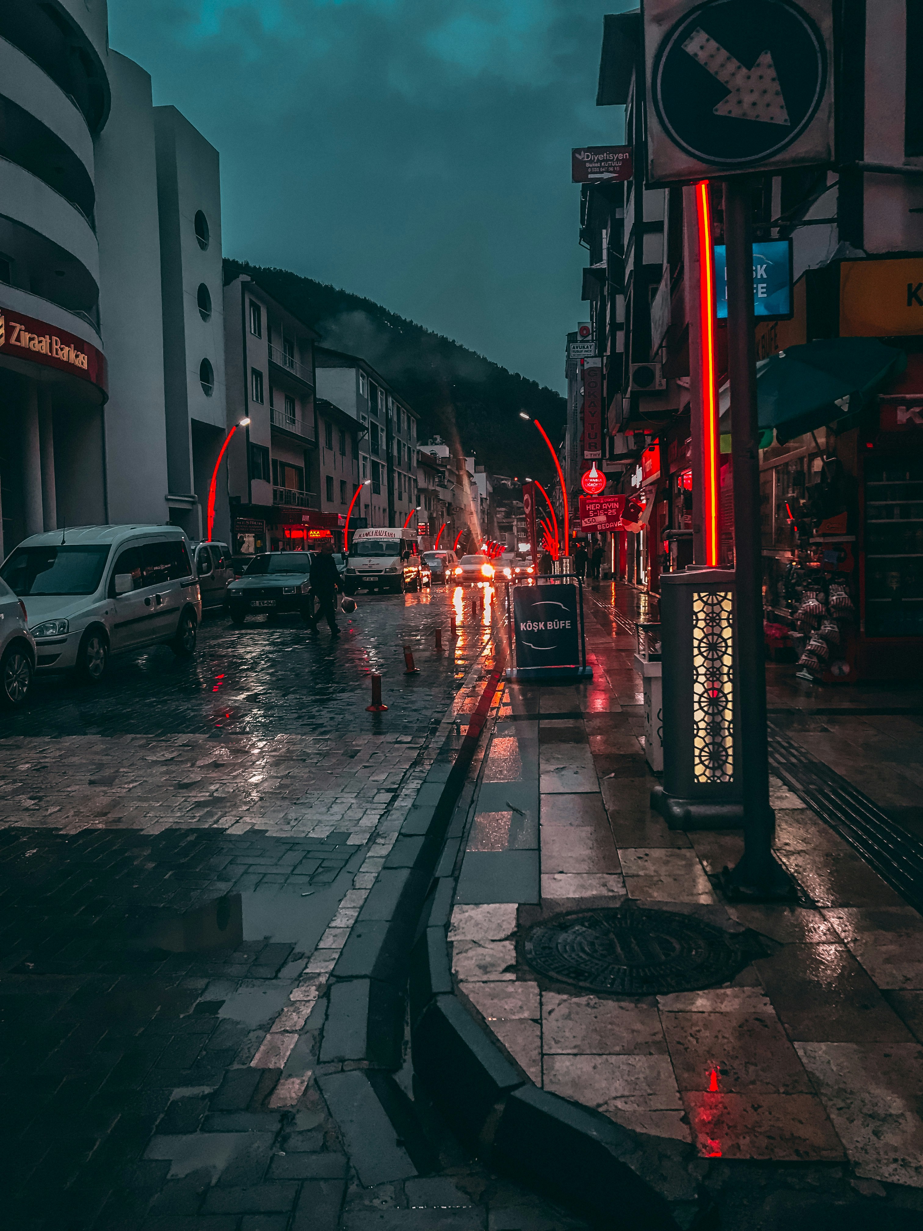 Una calle de la ciudad por la noche con coches aparcados al costado de la carretera