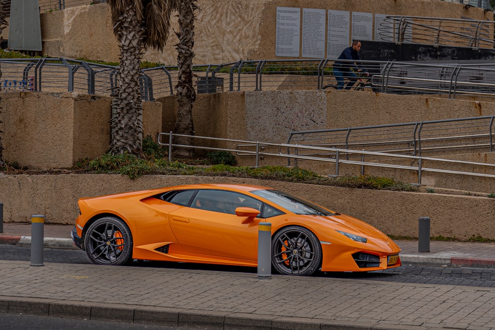 an orange sports car parked on the side of the road