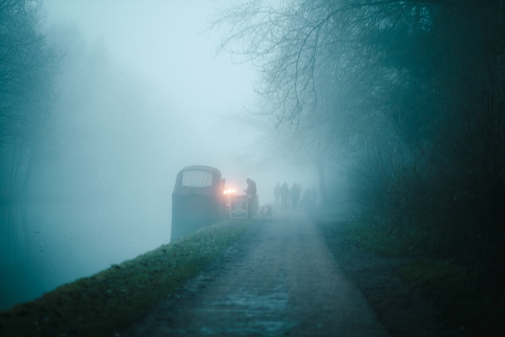 a bus driving down a foggy road next to a forest