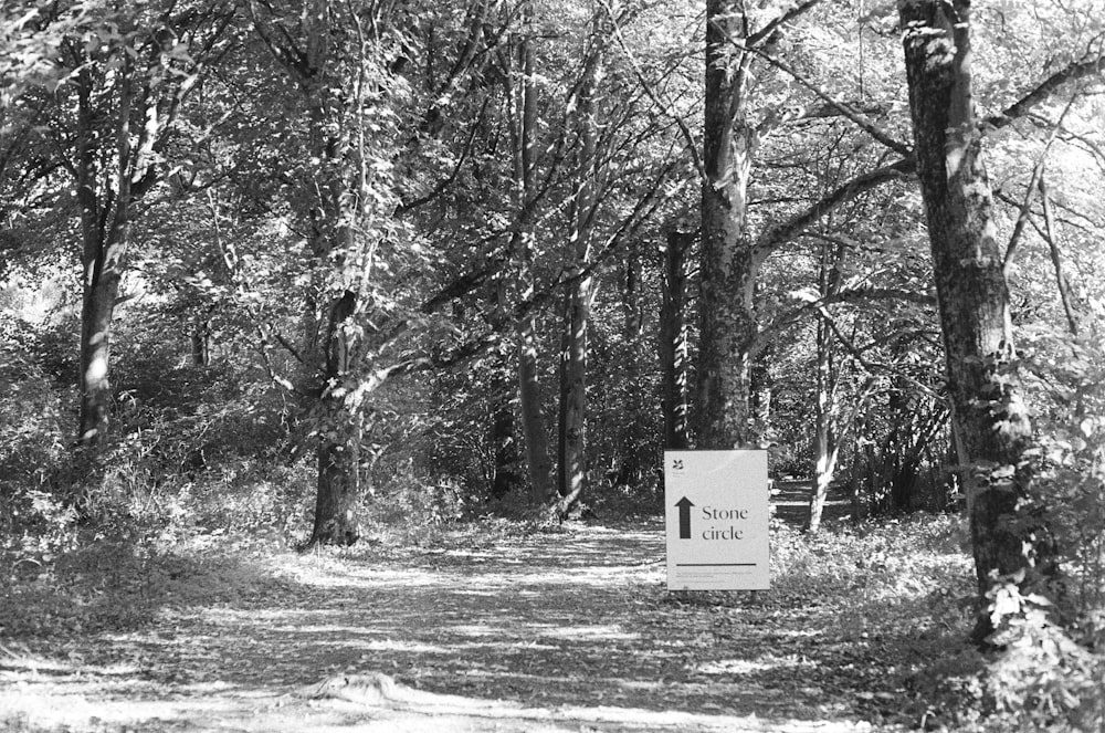 a black and white photo of a sign in the woods