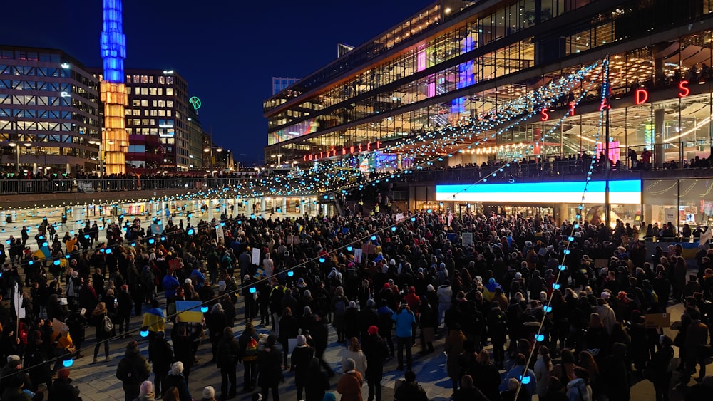 a crowd of people standing around a building at night