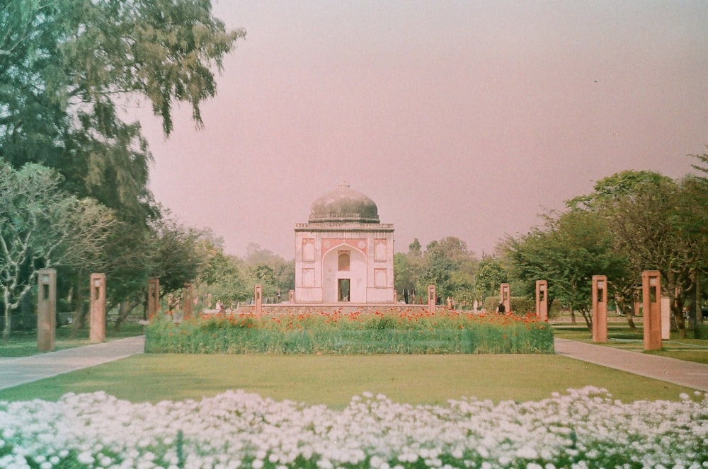 a large white building surrounded by trees and flowers