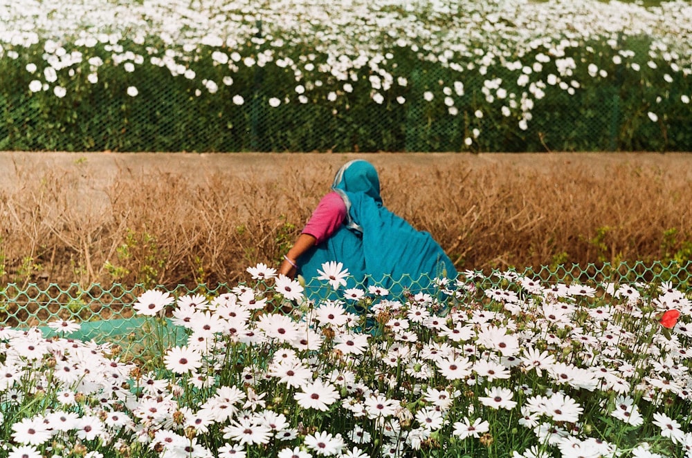a woman walking through a field of daisies
