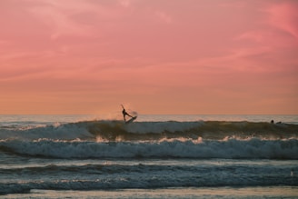 A surfer catching a perfect wave at sunrise with a vibrant sky.