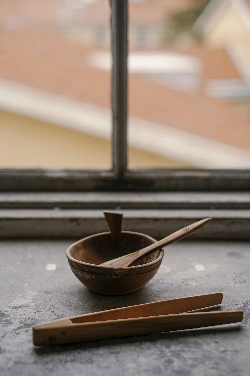 a wooden bowl and chopsticks on a window sill