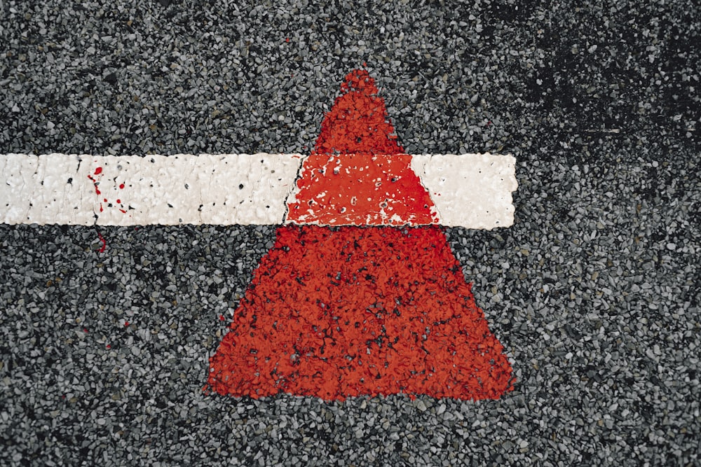 a red and white arrow painted on a road