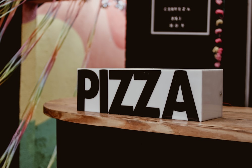 a sign that says pizza on a wooden table