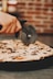 a person cutting a pizza with a pizza cutter