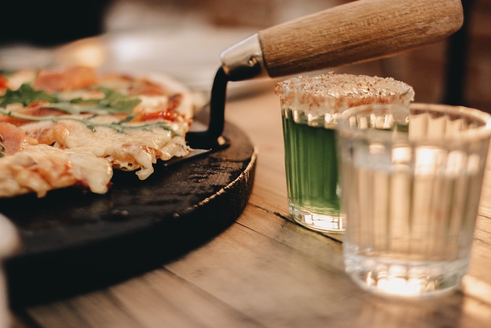 a pizza sitting on top of a wooden table next to a glass of water