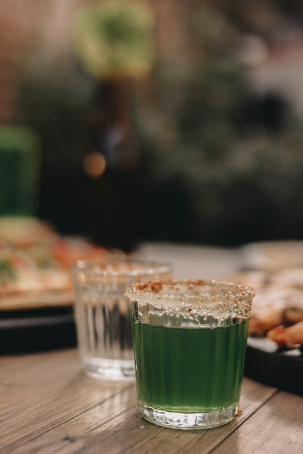 un bicchiere di liquido verde seduto sopra un tavolo di legno