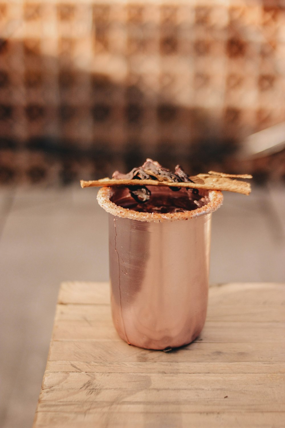 a metal cup filled with food on top of a wooden table