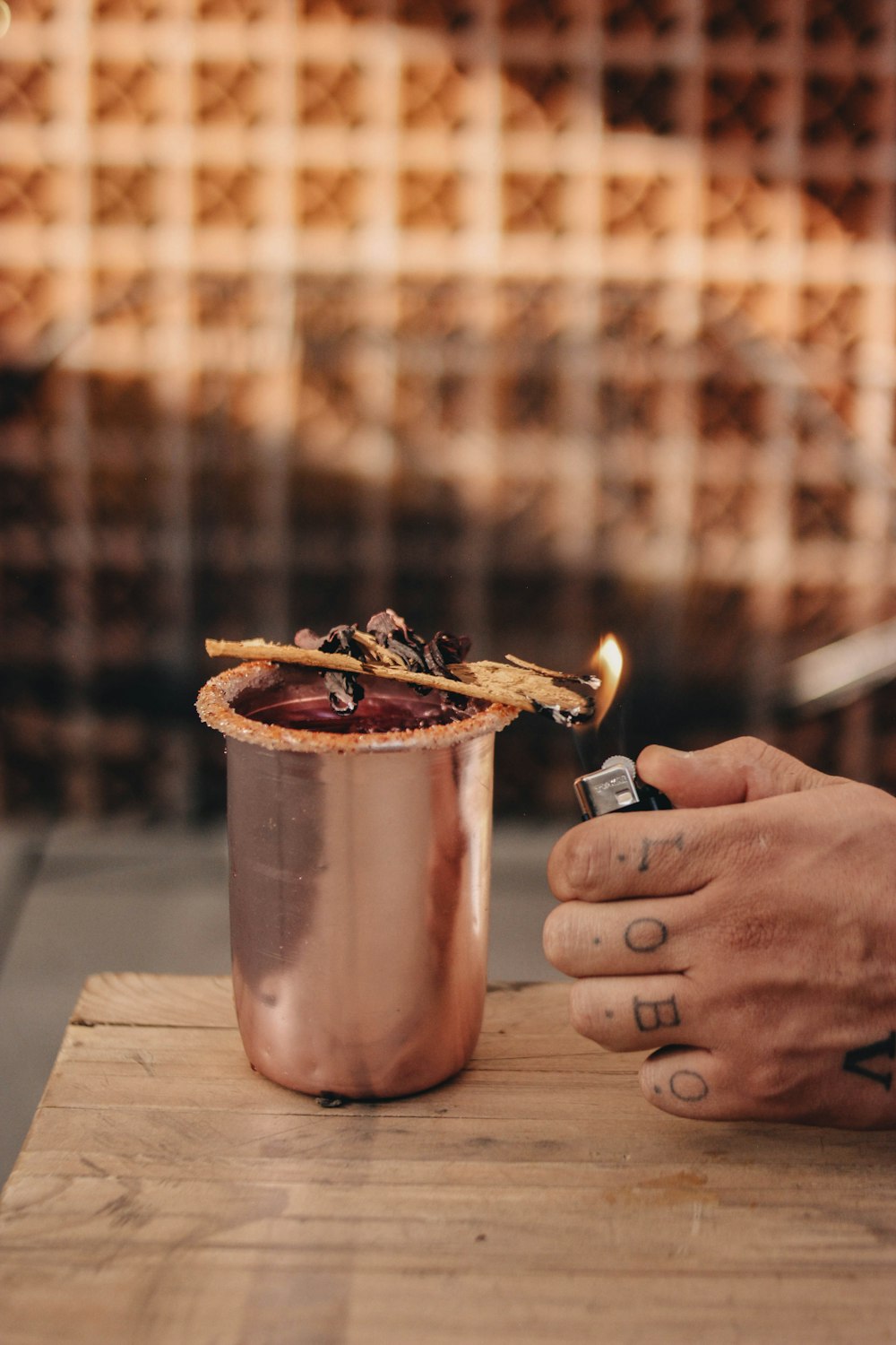 a person lighting a cigarette next to a copper cup