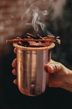 a person holding a metal cup with smoke coming out of it