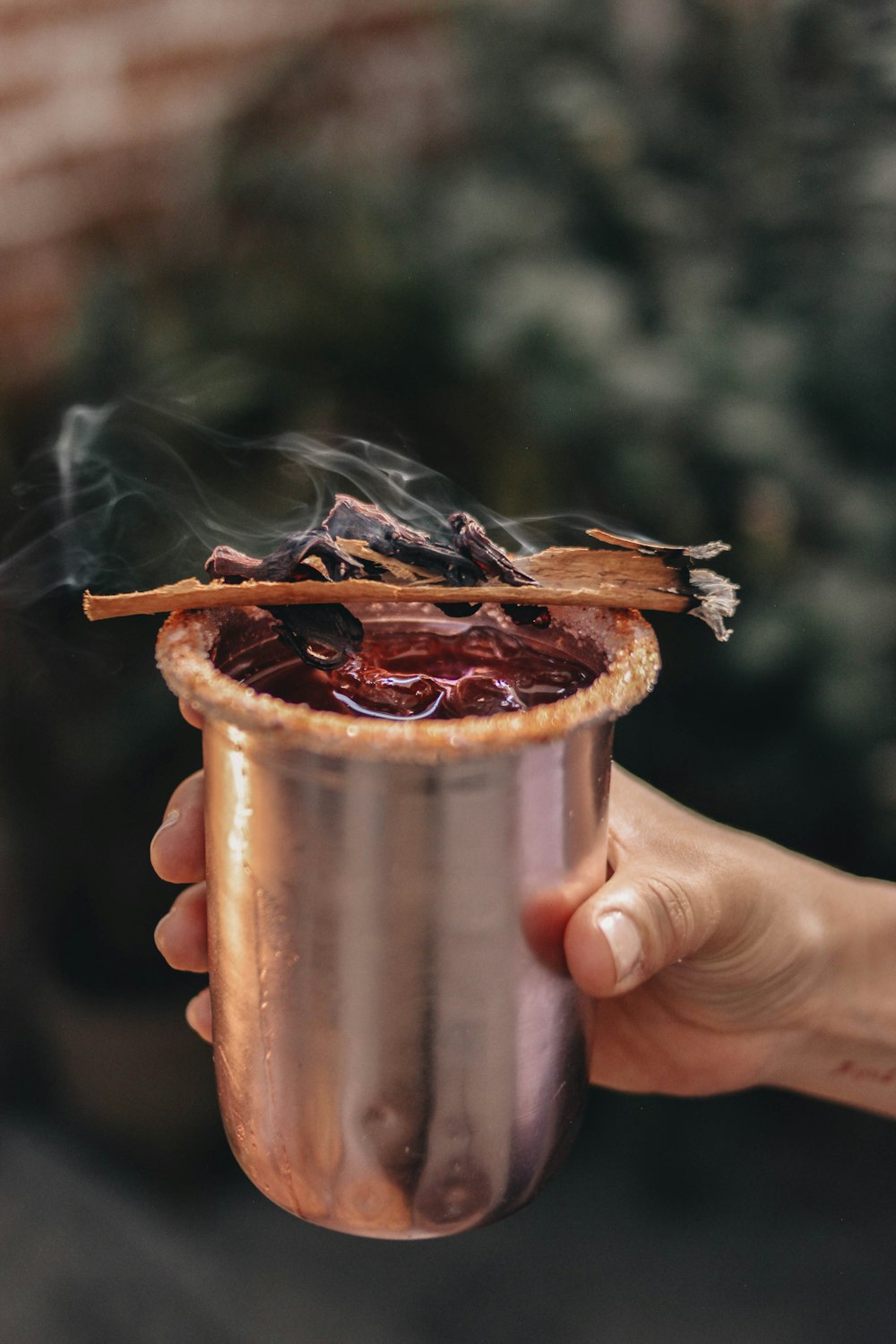 a person holding a copper cup with smoke coming out of it