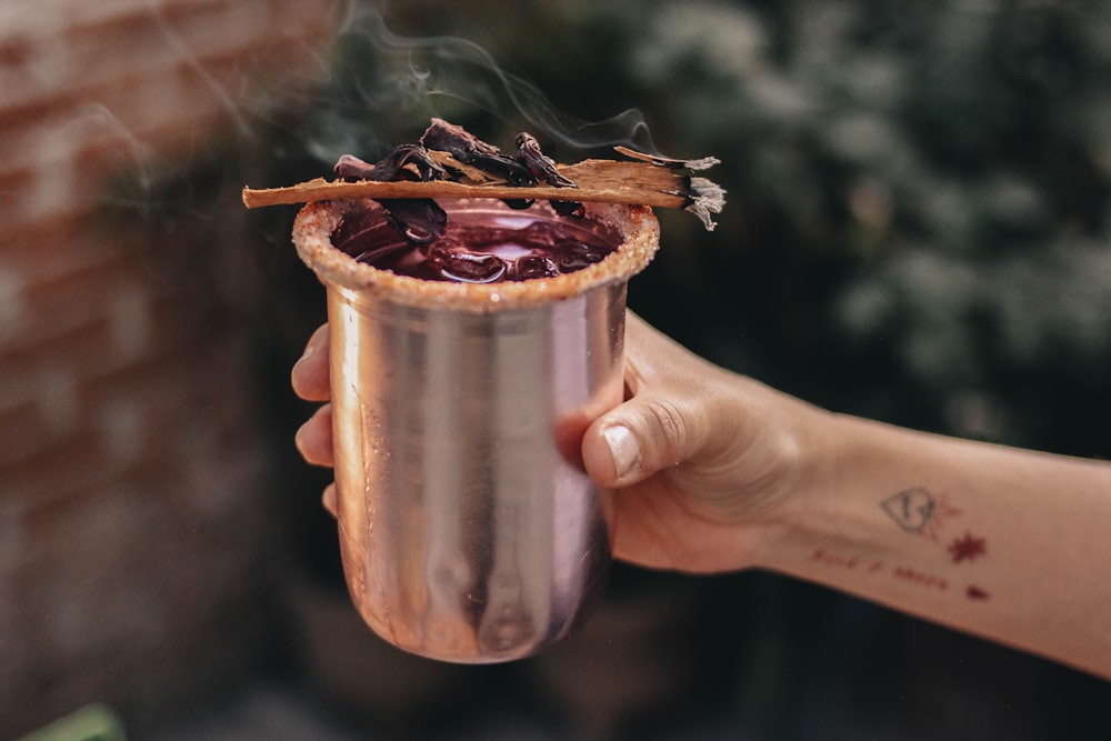 a person holding a metal cup filled with liquid