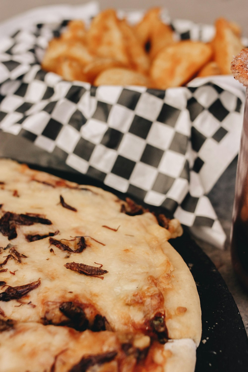 a pizza sitting on top of a pan next to a basket of fries