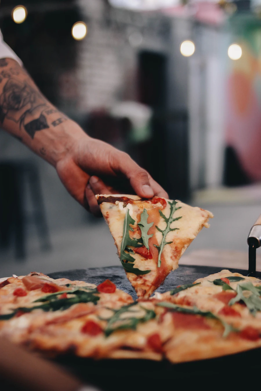 Fatia suculenta de pizza sendo cortada, com queijo derretendo