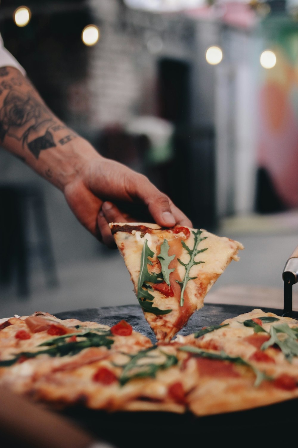 a person cutting a slice of pizza with a pizza cutter