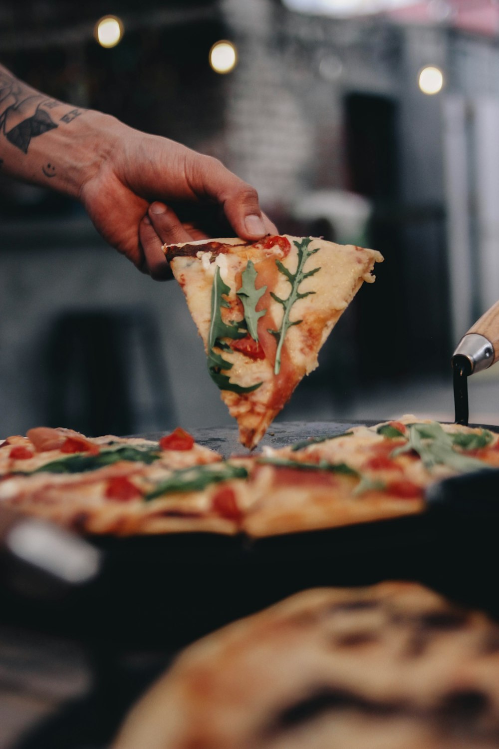 a person cutting a slice of pizza with a knife