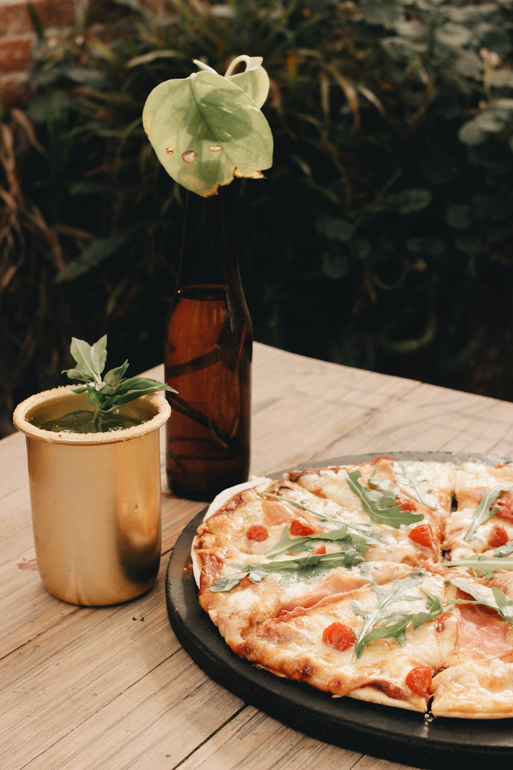 a pizza sitting on top of a wooden table next to a potted plant