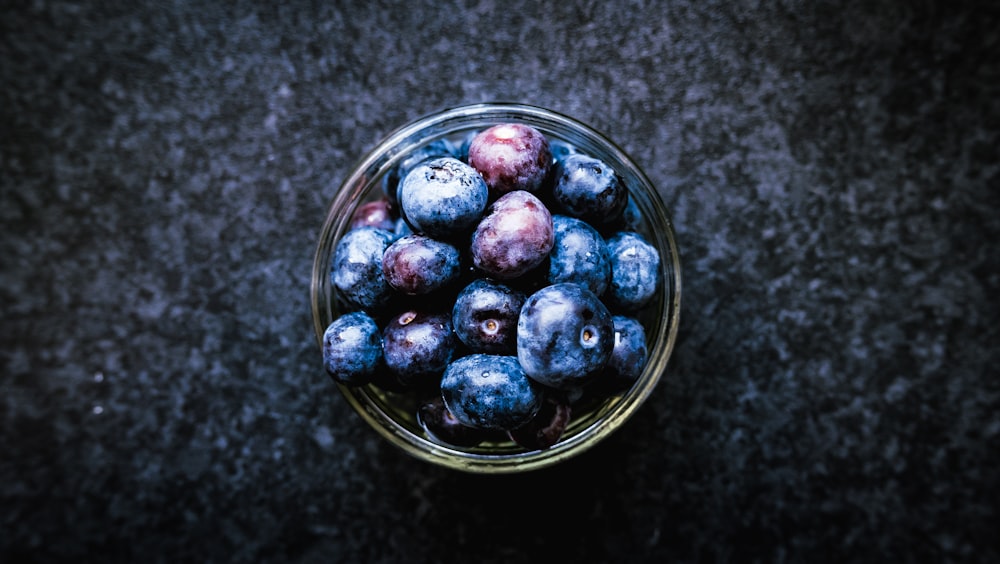a glass bowl filled with blueberries on top of a table