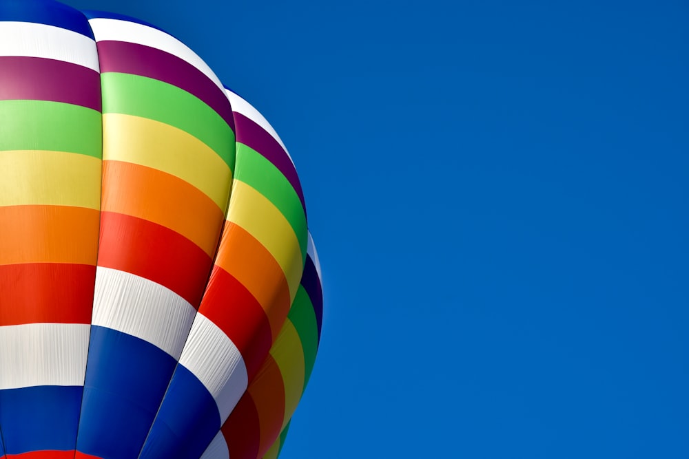 a multicolored hot air balloon flying in a blue sky