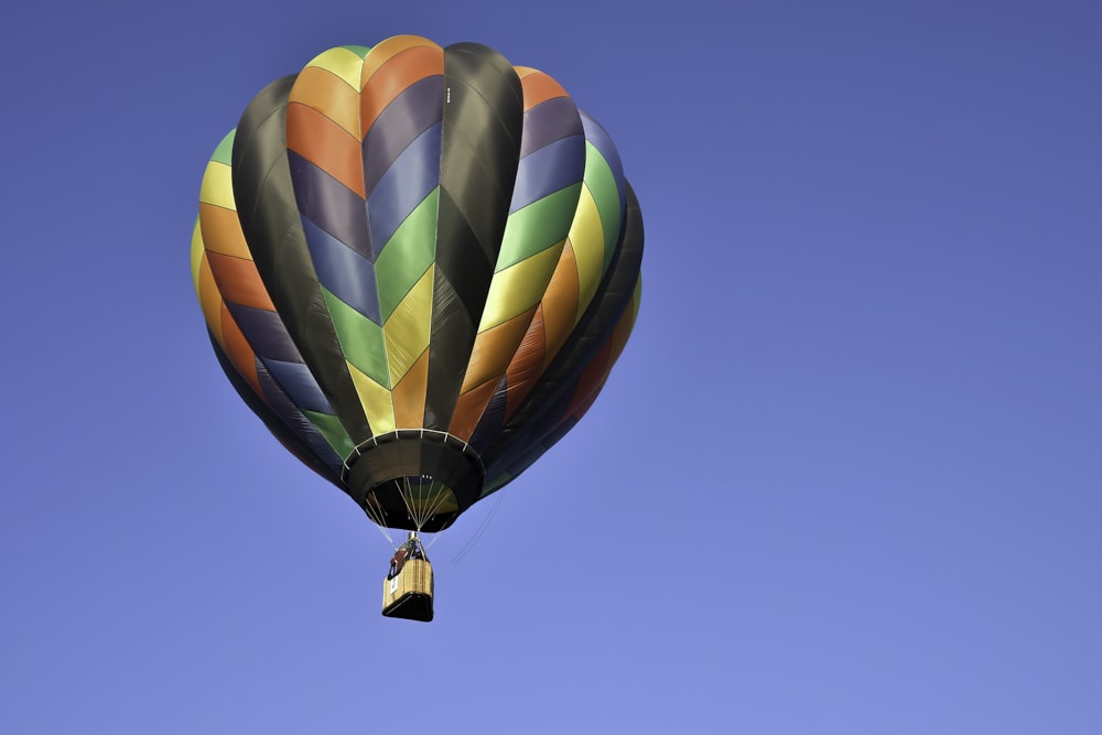 Ein bunter Heißluftballon, der durch einen blauen Himmel fliegt