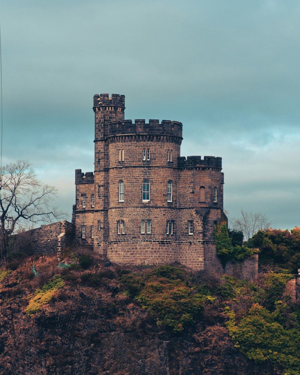 a castle sitting on top of a hill next to a forest