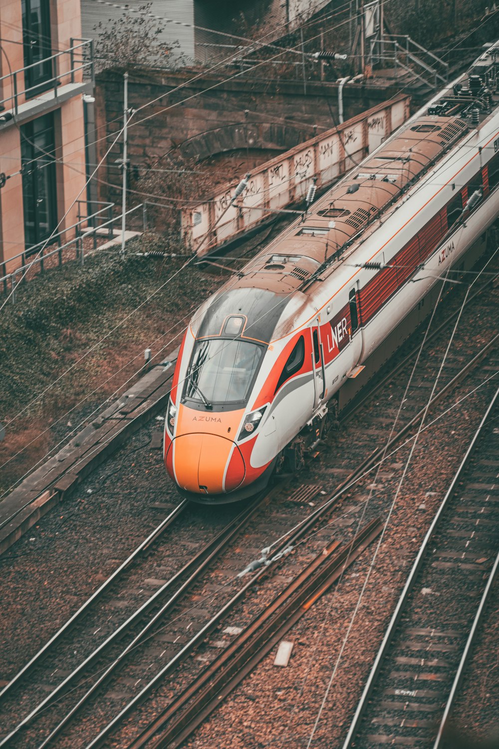 an orange and white train traveling down train tracks