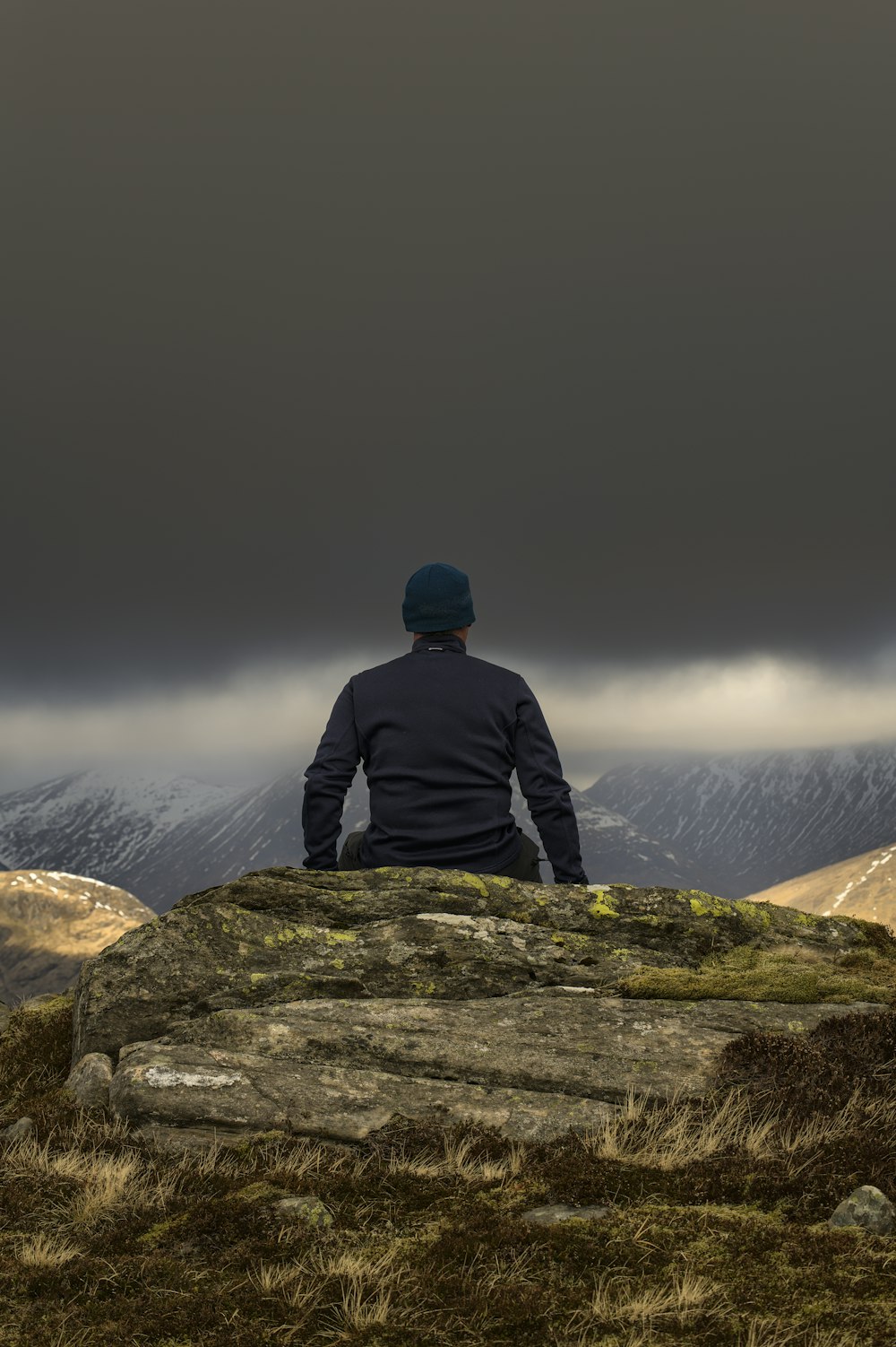 a man sitting on top of a large rock