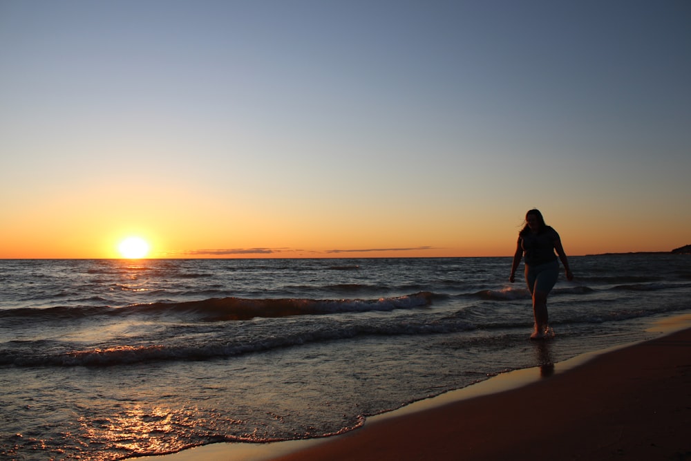 a person walking on the beach at sunset