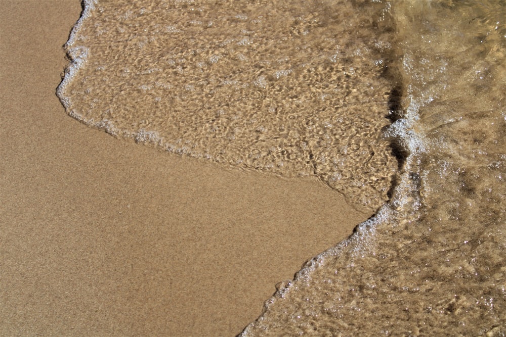 a sandy beach with a wave coming in to shore