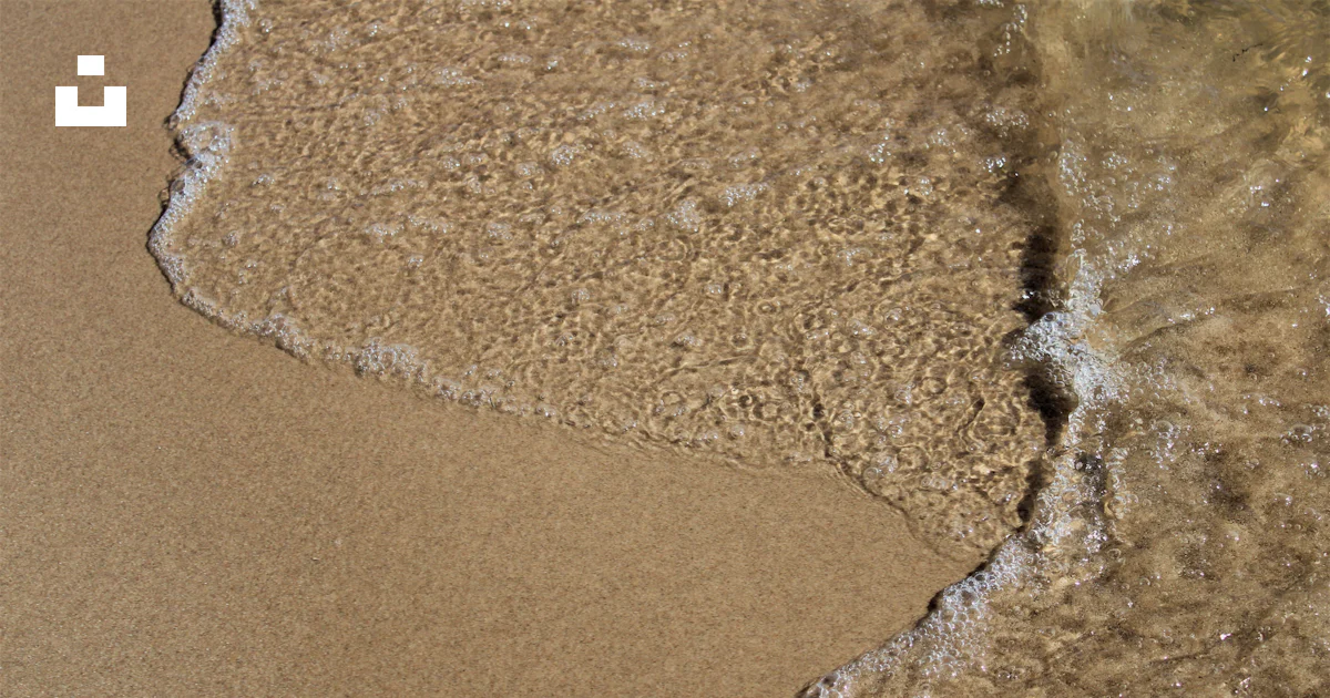 Une plage de sable avec une vague arrivant sur le rivage photo – Photo ...