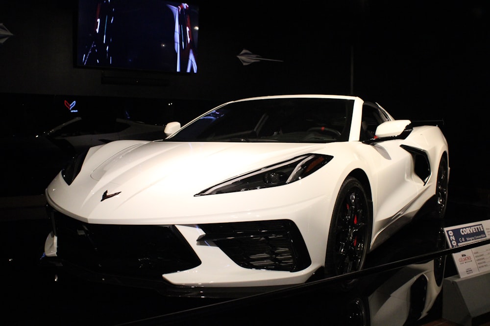 a white sports car on display in a dark room