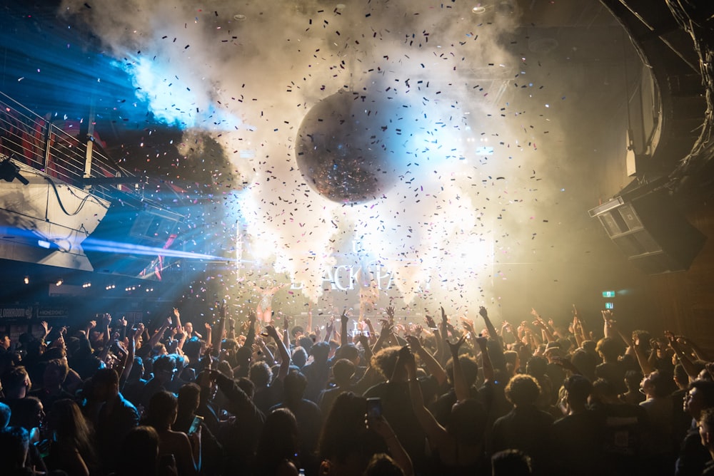 a crowd of people at a concert with confetti in the air