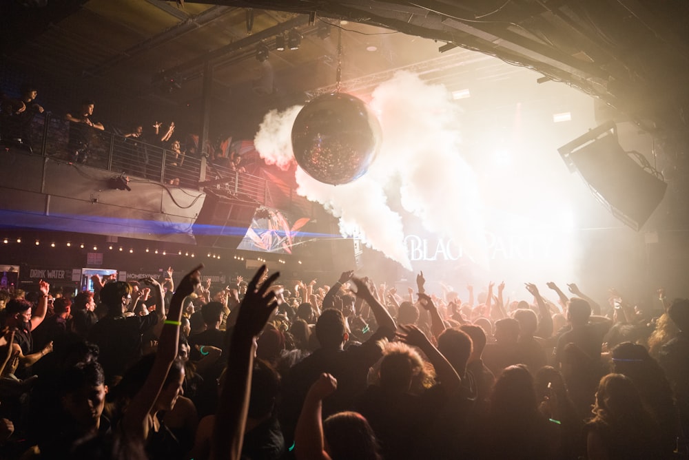 a crowd of people at a concert with their hands in the air