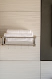 Modern bathroom with clean white tiles and fresh towels neatly arranged.