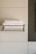 A modern bathroom scene with neatly folded white towels resting on a metallic towel rack against a textured, light-colored wall. The design features clean lines and a minimalist aesthetic.
