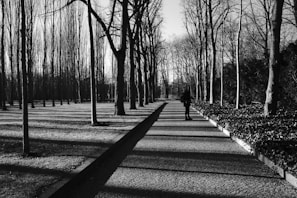 A black and white photo of Olga walking alone on a path surrounded by trees, representing the journey through struggle.