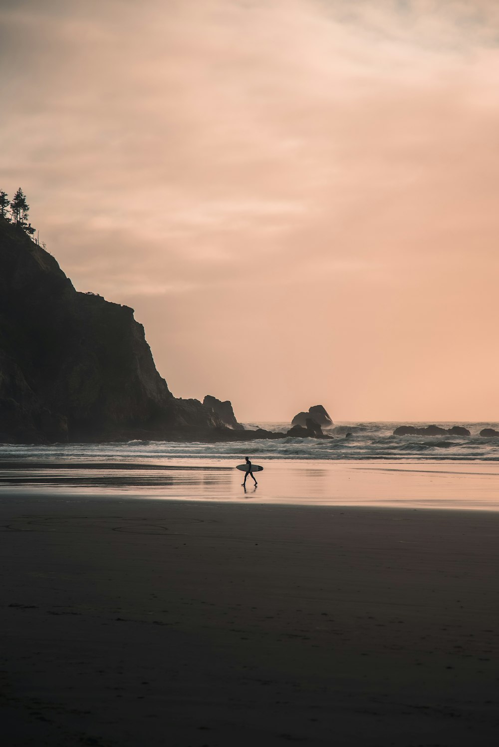 a person walking on a beach carrying a surfboard