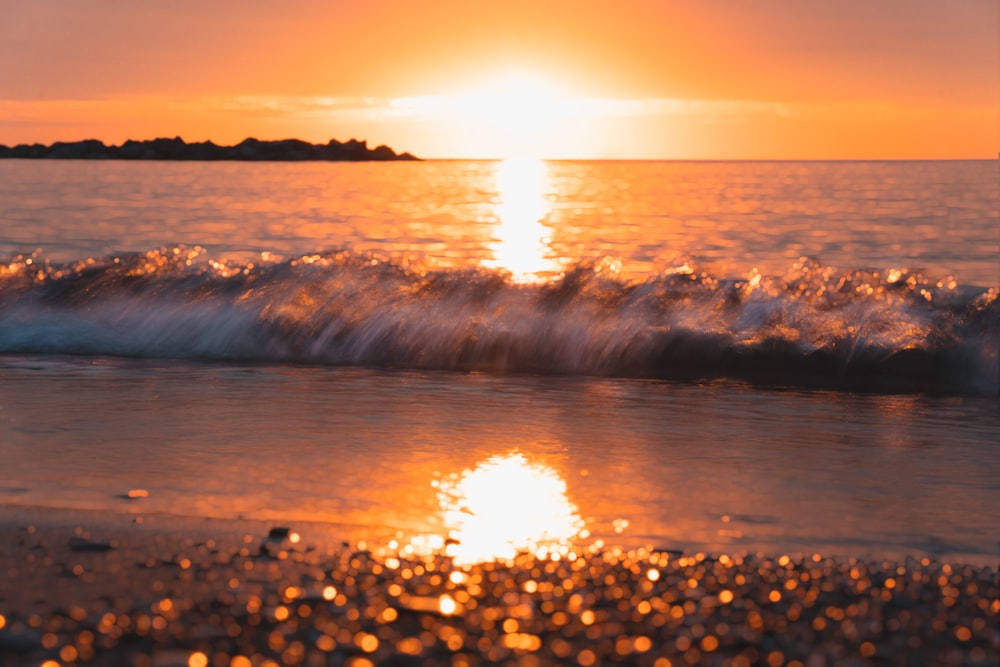 the sun is setting over the water at the beach