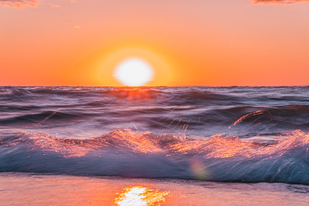 the sun is setting over the ocean waves