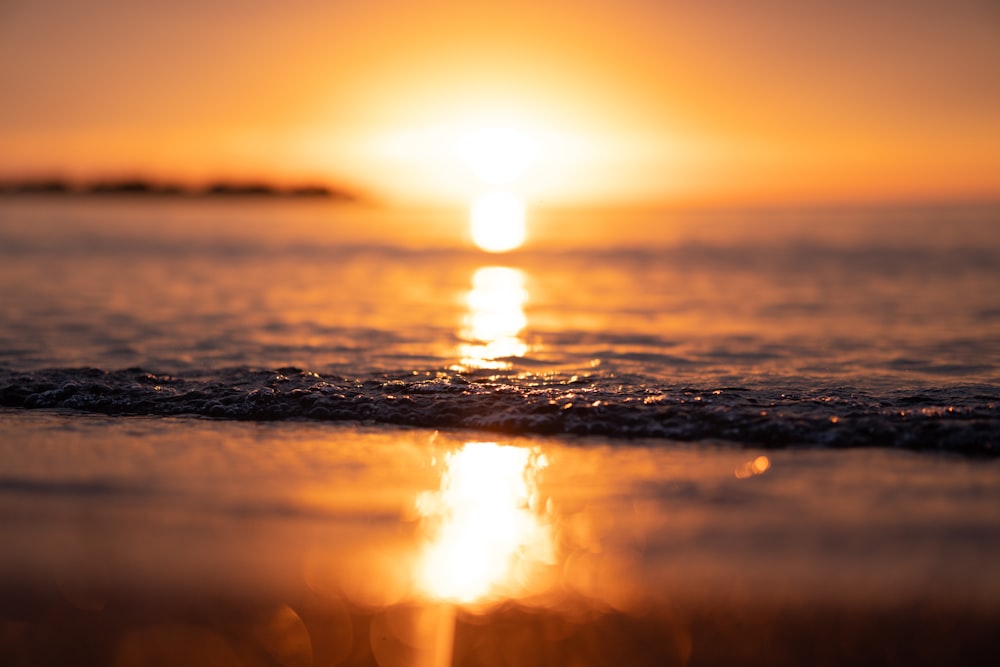 the sun is setting over the water at the beach