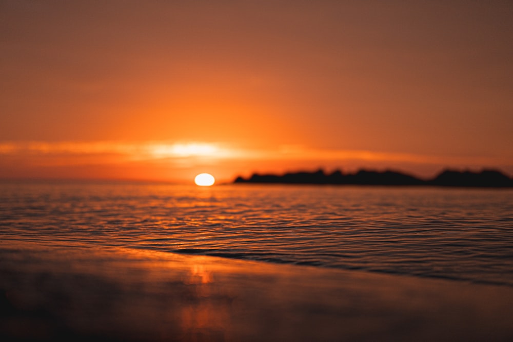 the sun is setting over a small island in the ocean