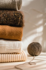 a stack of sweaters and a ball of yarn